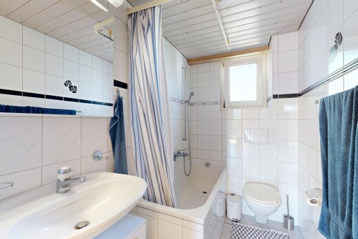 bathroom with tile walls, tiled shower / bath, and light tile patterned flooring