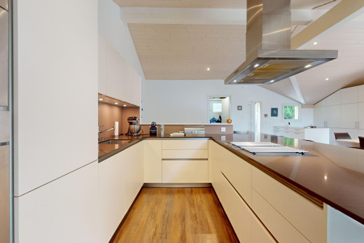 küche mit natürliches licht, arbeitsplatten, dachschräge, schränke mit flachen paneelen, und dunstabzugshaube