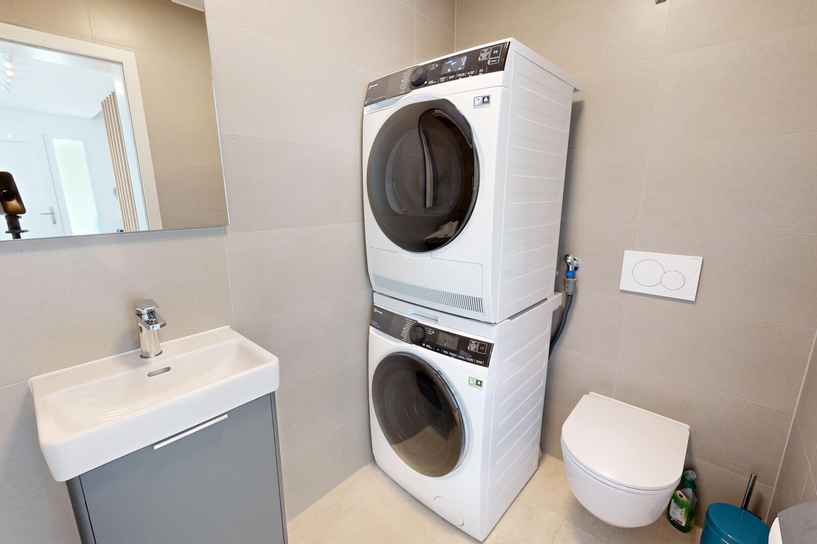 buanderie avec buanderie, évier, lave-linge et sèche-linge superposés, tile wall, et mur en carrelage