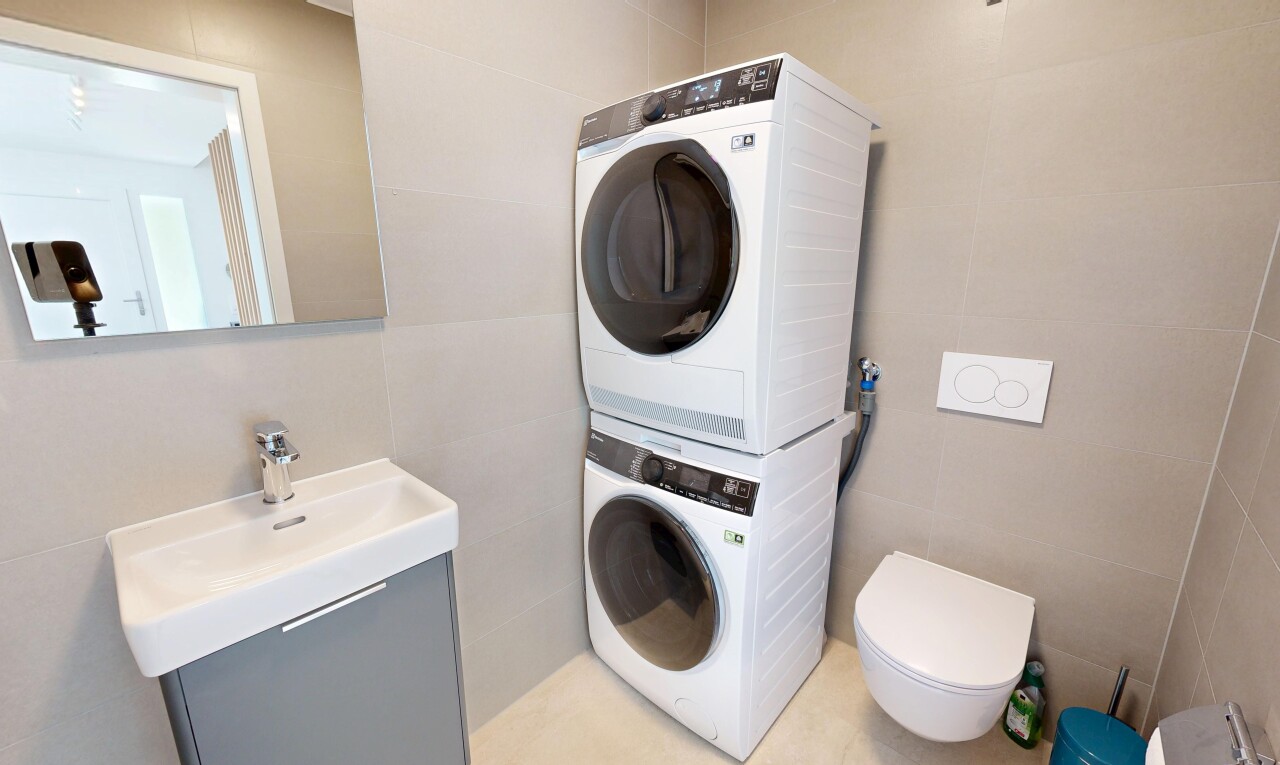 buanderie avec buanderie, évier, lave-linge et sèche-linge superposés, tile wall, et mur en carrelage