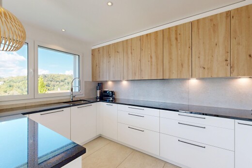 cuisine avec dark countertops, flat panel cabinets, armoires à panneau plat, two tone kitchen, et day time