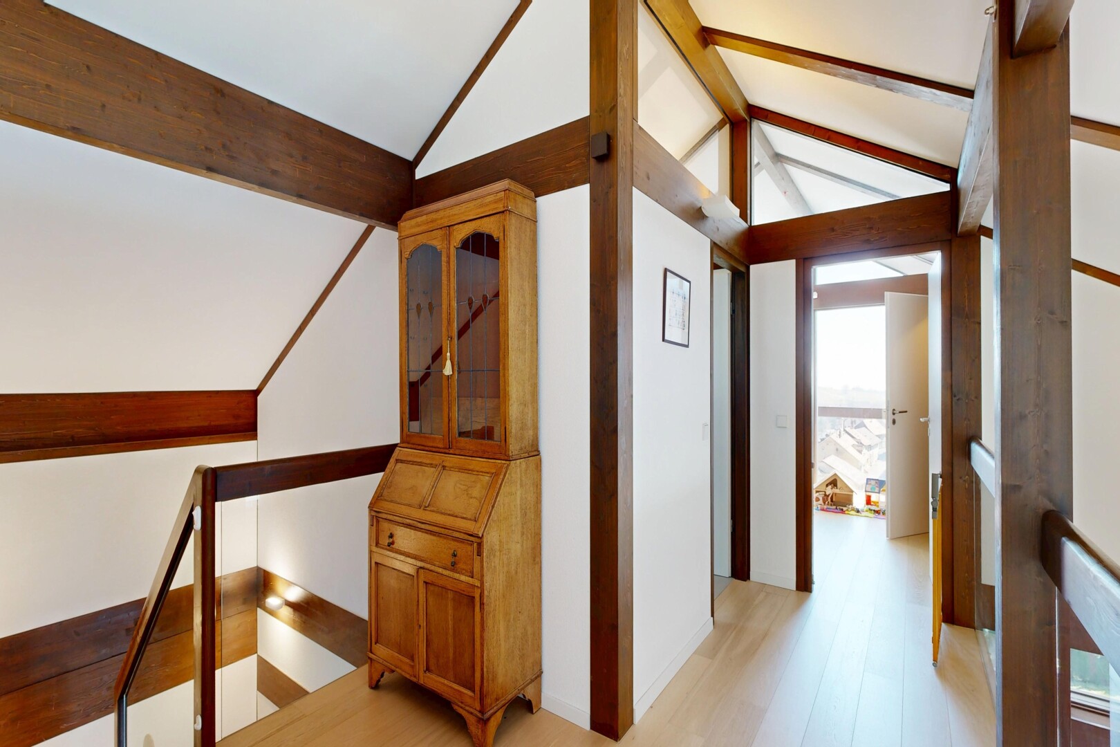 couloir avec palier à l'étage, plafond voûté, vaulted ceiling, sol en finition bois, et wood finish floor