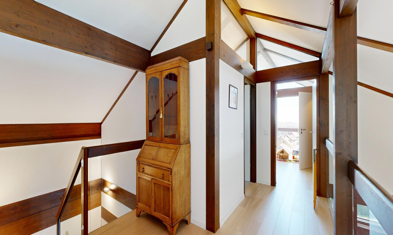couloir avec palier à l'étage, plafond voûté, vaulted ceiling, sol en finition bois, et wood finish floor