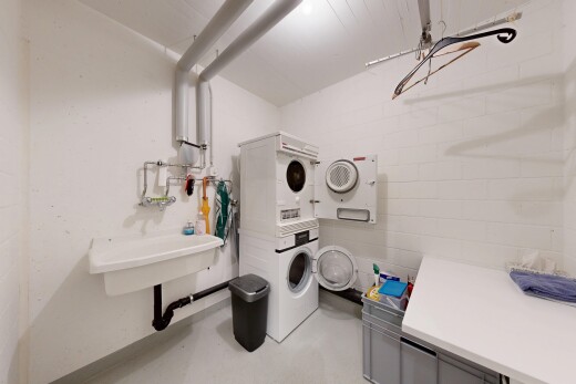 laundry room with stacked washer / dryer, concrete block wall, and concrete flooring