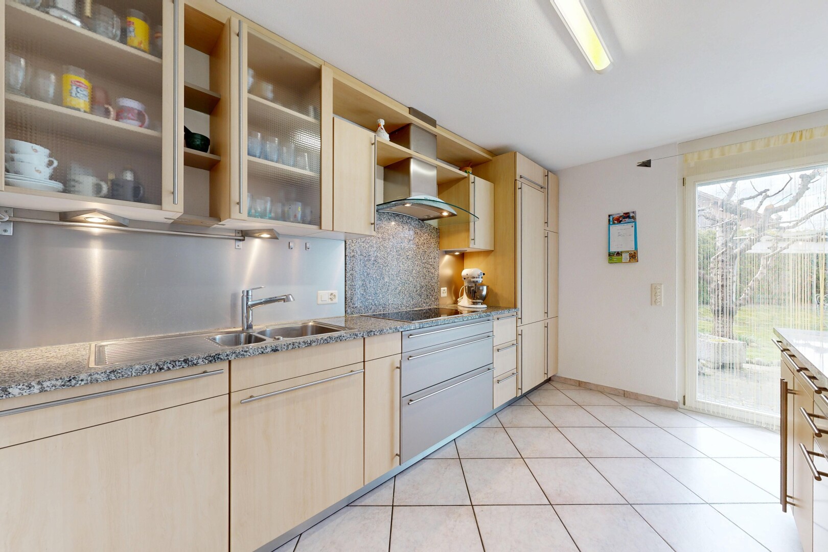 cuisine avec light brown cabinets, armoires marron clair, light floor, hotte, et backsplash