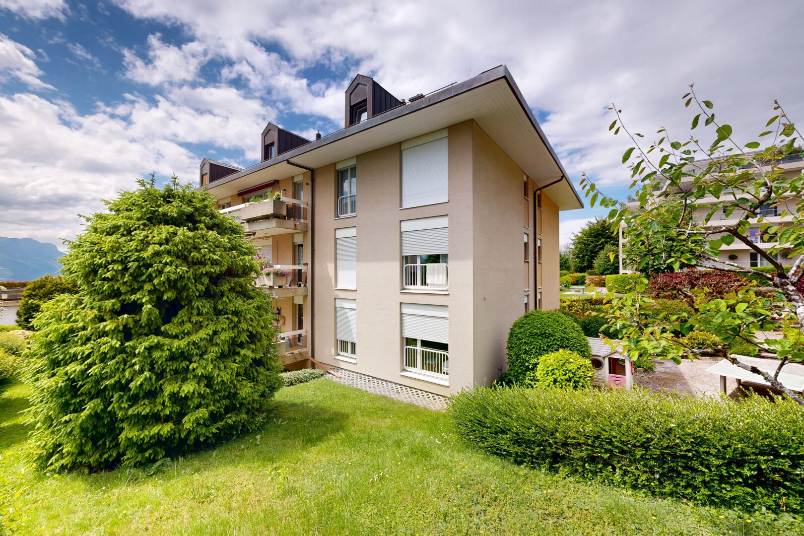façade avec bardage en stuc, toit mansardé, pelouse, day time, et apartment complex view