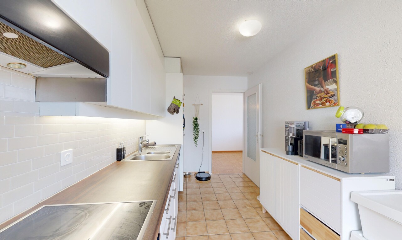 cuisine avec white cabinets, armoires blanches, hotte, micro-ondes, et light countertops