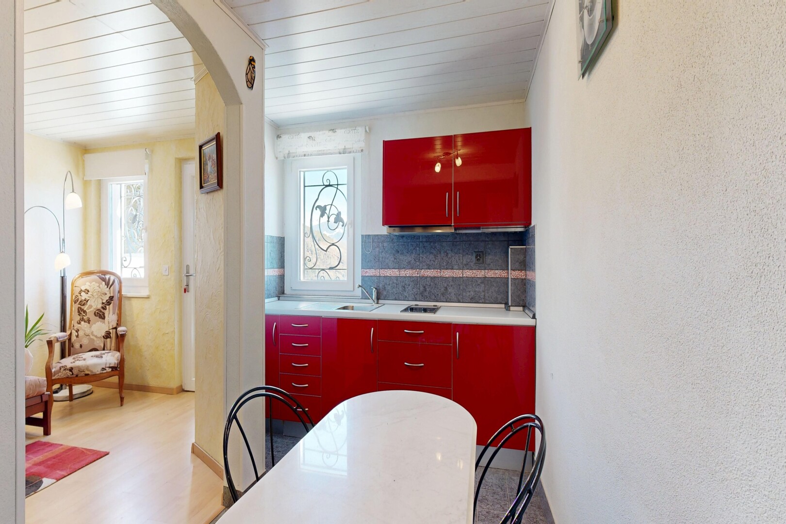 cuisine avec red cabinets, armoires rouges, natural light, lumière naturelle, et backsplash