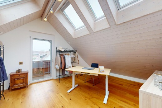 bureau avec plafond voûté, puits de lumière, sol en finition bois, pièce supplémentaire, et plafond à poutres