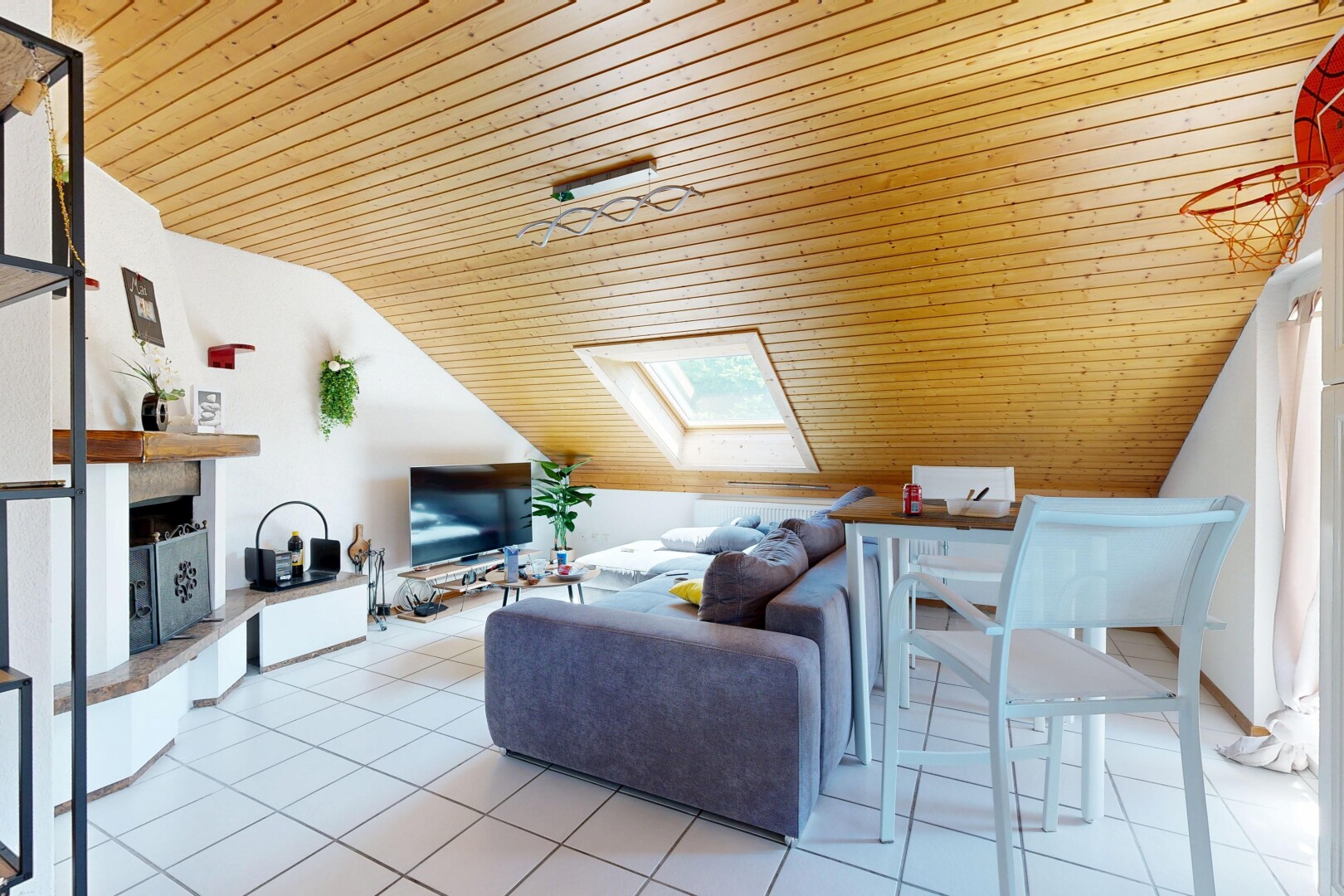 living area with a vaulted wood ceiling, a fireplace with raised hearth, and a skylight