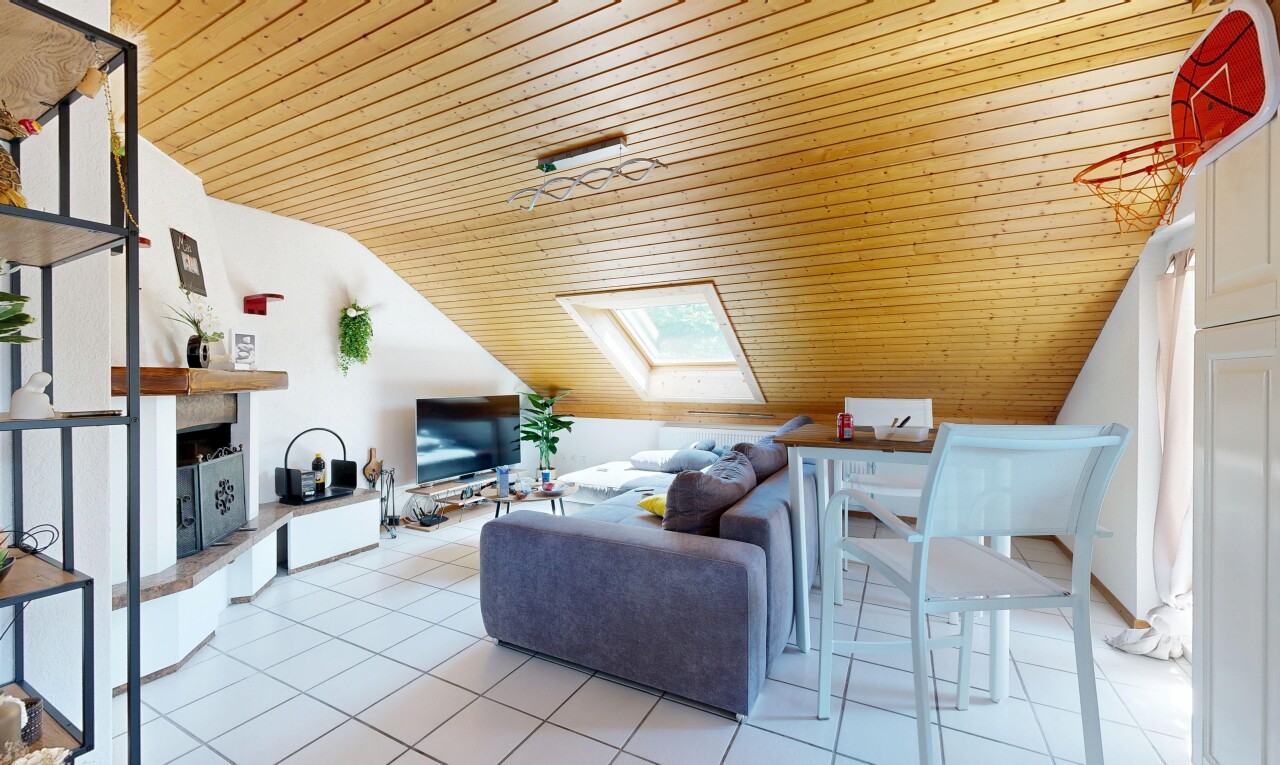 living area with a vaulted wood ceiling, a fireplace with raised hearth, and a skylight