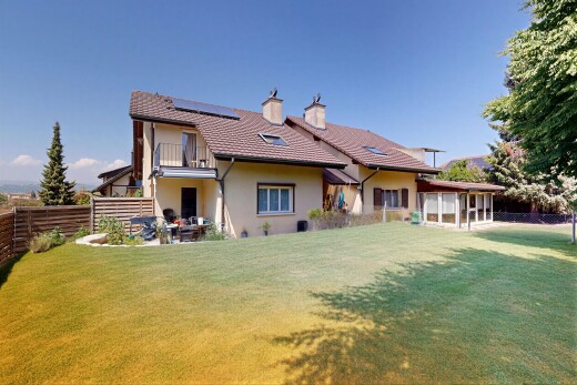 view of property featuring a fenced backyard, roof mounted solar panels, stucco siding, a balcony, and a chimney