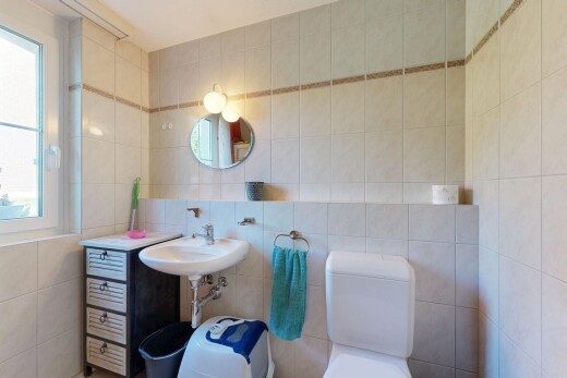 salle de bains avec tile wall, mur en carrelage, miroir, toilette, et natural light