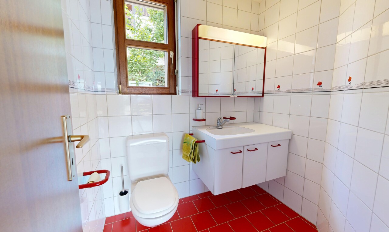 salle de bains avec lavabo (ou coiffeuse selon le contexte), dark floor, miroir, toilette, et mur en carrelage