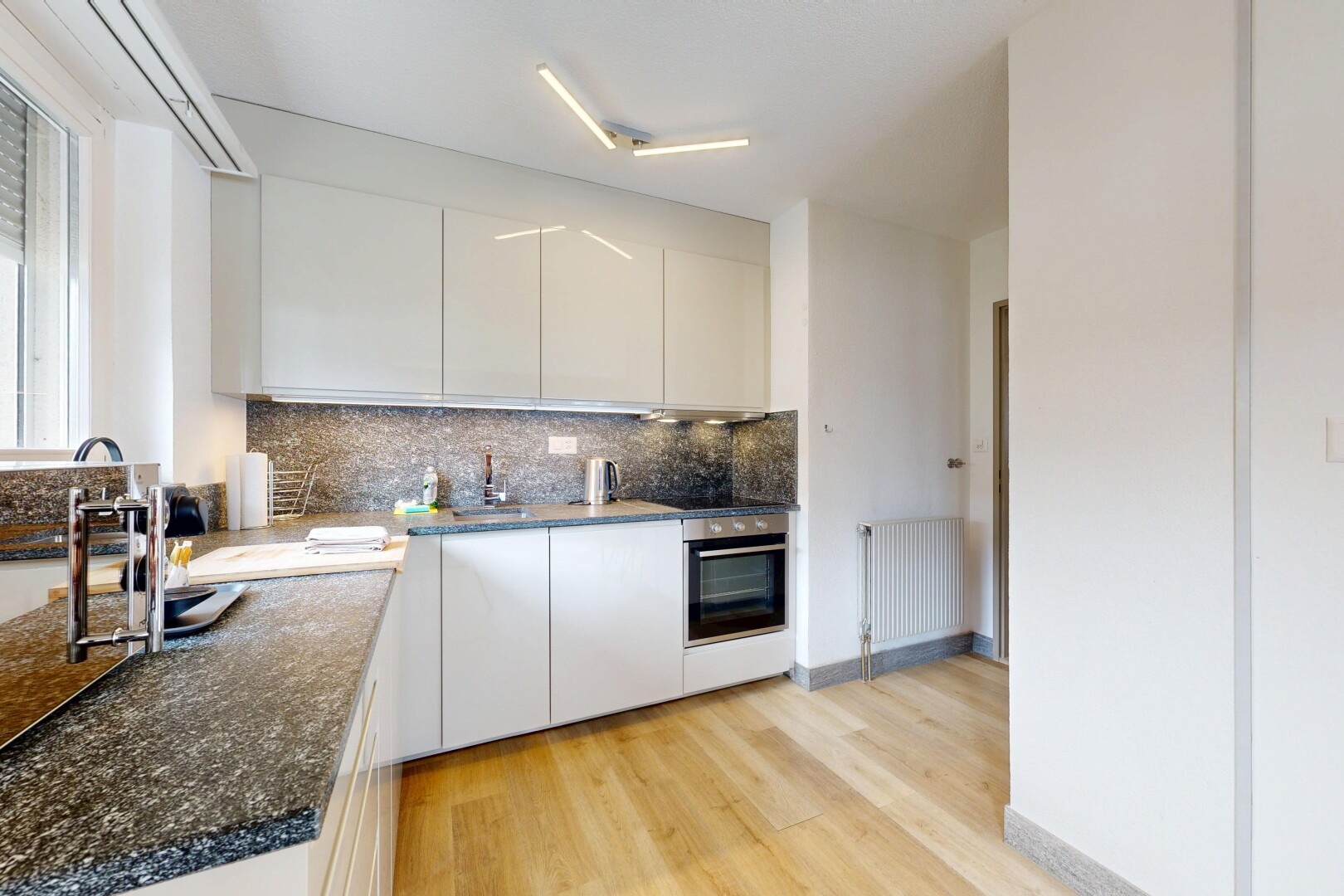cuisine avec light floor, sol en finition bois, wood finish floor, radiateur, et four