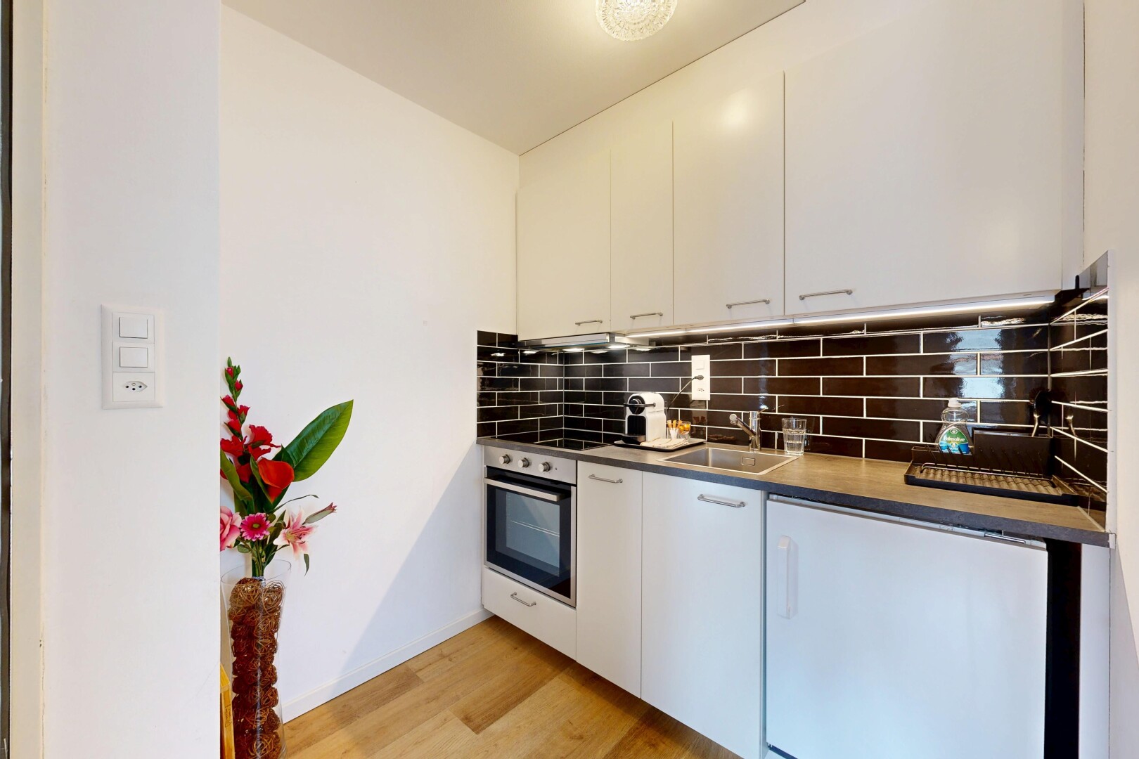 cuisine avec light floor, four, backsplash, dosseret, et armoires blanches