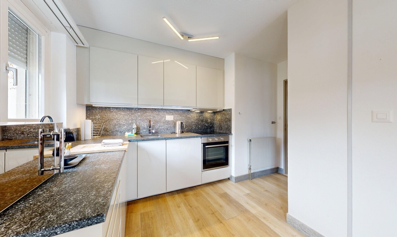 cuisine avec light floor, sol en finition bois, wood finish floor, radiateur, et four