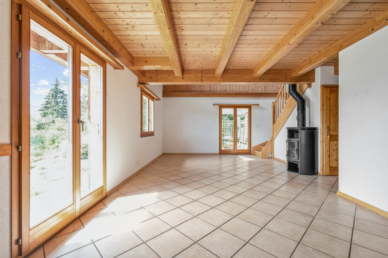 pièce vide avec beamed ceiling, plafond à poutres, poêle à bois, wood ceiling, et plafond en bois