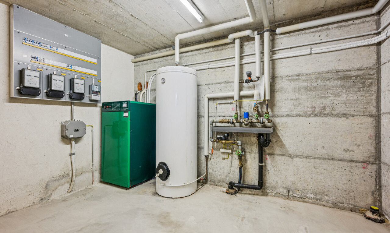buanderie avec concrete wall, chaudière, concrete ceiling, concrete floor, et chauffe-eau