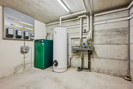 buanderie avec concrete wall, chaudière, concrete ceiling, concrete floor, et chauffe-eau
