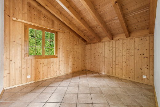 pièce vide avec vaulted ceiling, plafond voûté, beamed ceiling, plafond à poutres, et wood wall