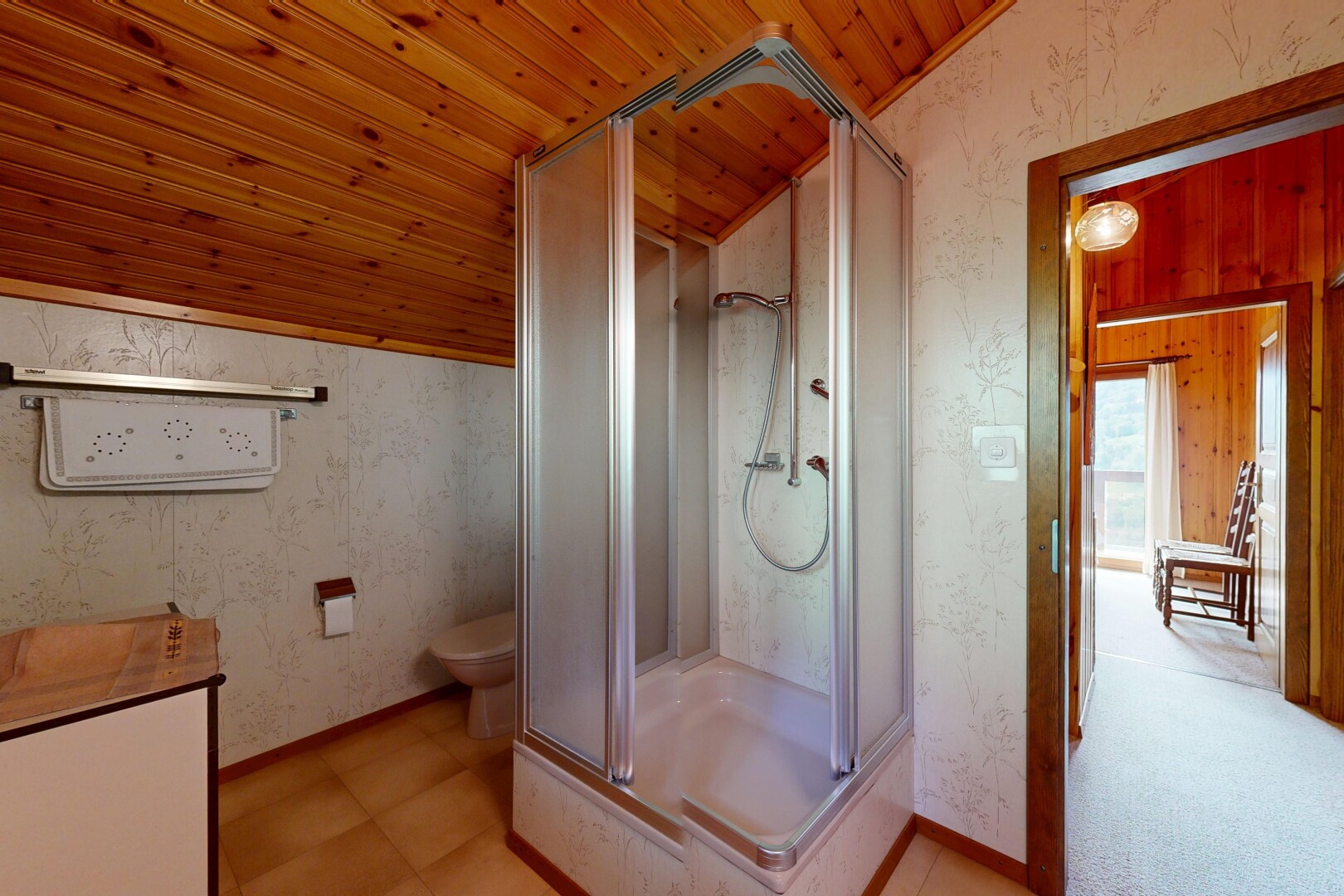 salle de bains avec wallpaper wall, mur en papier peint, douche, vaulted ceiling, et plafond voûté