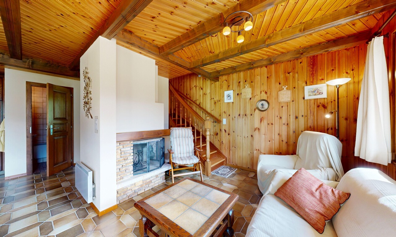 salon avec escaliers, cheminée, inside property, radiateur, et plafond à poutres