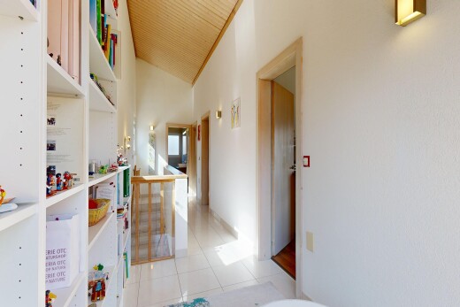 hallway featuring light tile patterned floors and lofted ceiling