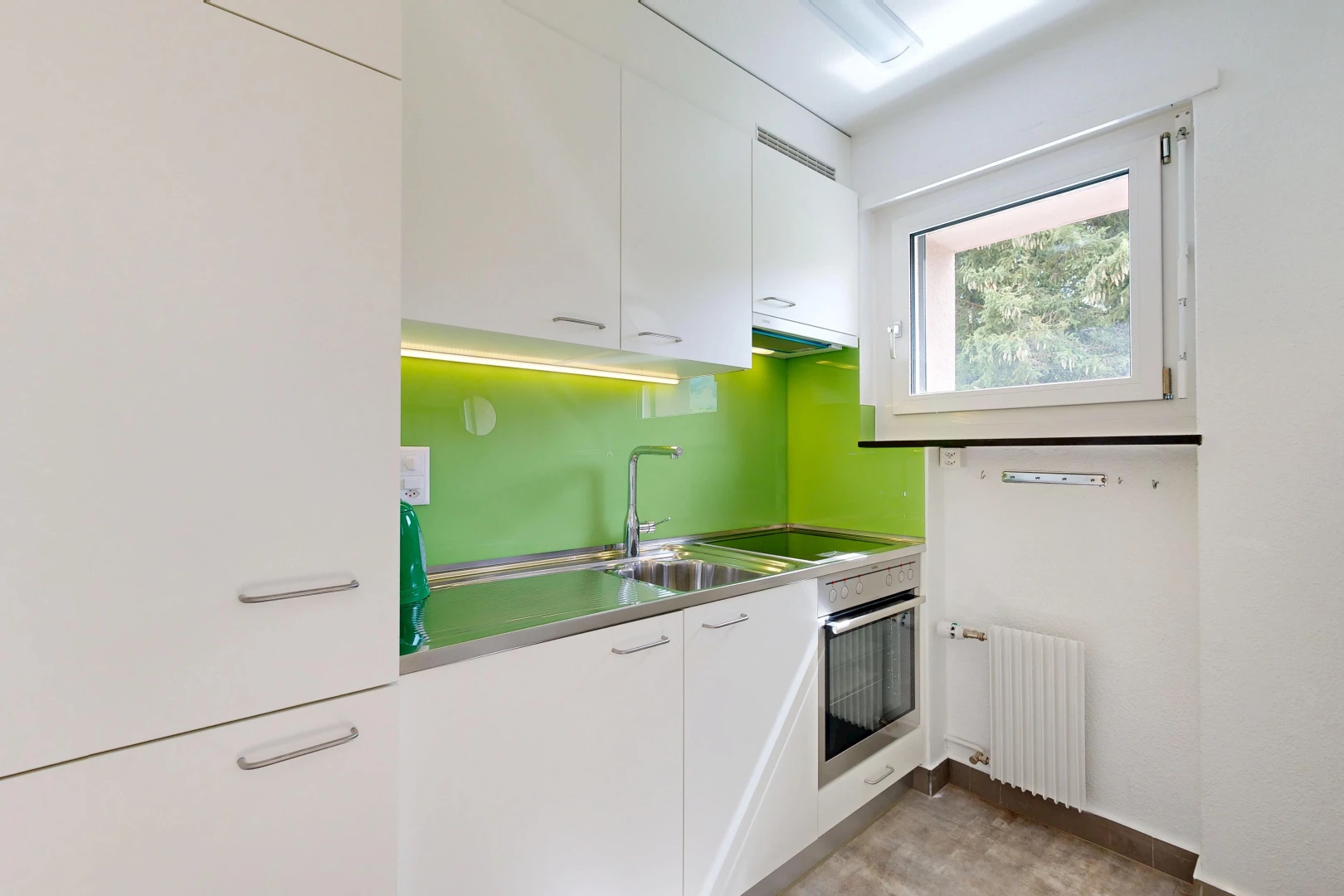 cuisine avec plans de travail en acier inoxydable, stainless steel countertops, armoires blanches, white cabinets, et radiateur