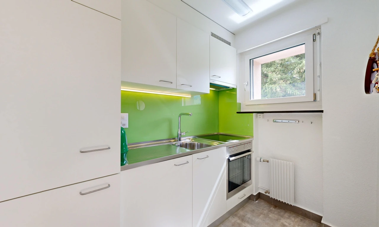 cuisine avec plans de travail en acier inoxydable, stainless steel countertops, armoires blanches, white cabinets, et radiateur