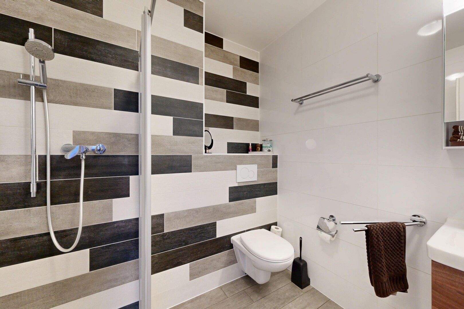salle de bains avec salle de bain complète, douche, miroir, lavabo (ou coiffeuse selon le contexte), et mur en carrelage