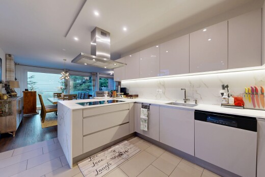 cuisine avec péninsule de cuisine, éclairage suspendu, lave-vaisselle, armoires à panneau plat, et armoires blanches