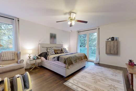 room / bedroom featuring access to exterior, multiple windows, dark wood-style floors, and ceiling fan
