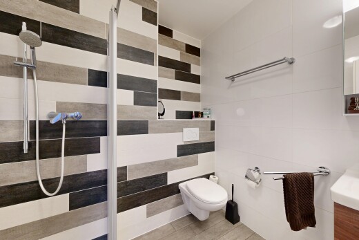 salle de bains avec salle de bain complète, douche, miroir, lavabo (ou coiffeuse selon le contexte), et mur en carrelage