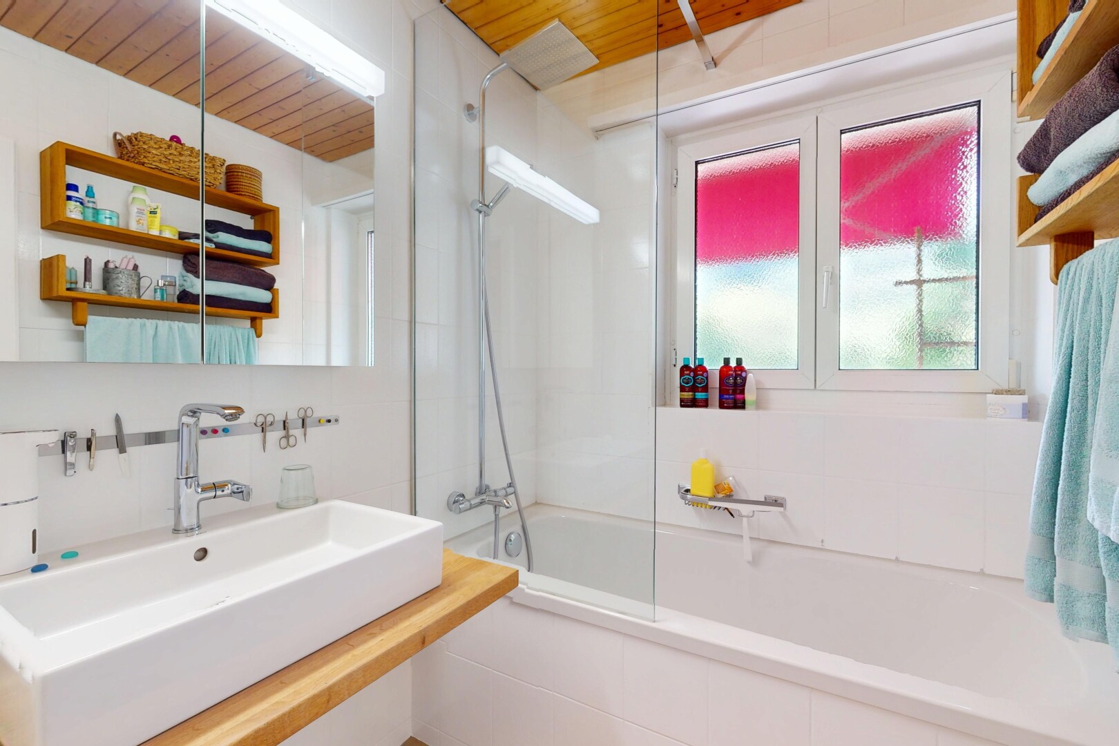 salle de bains avec douche-bain combinés, miroir, évier, natural light, et lumière naturelle
