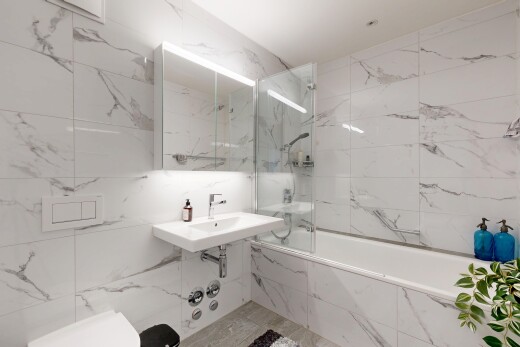 full bathroom featuring tile walls, a combined bath / shower with marble appearance, and stone wall