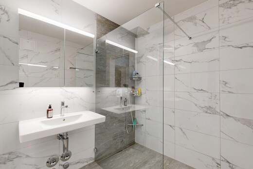 bathroom with a marble finish shower and tile walls