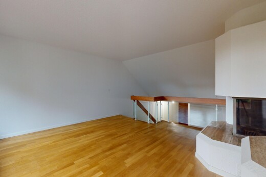 spare room featuring light wood finished floors, vaulted ceiling, and a glass covered fireplace