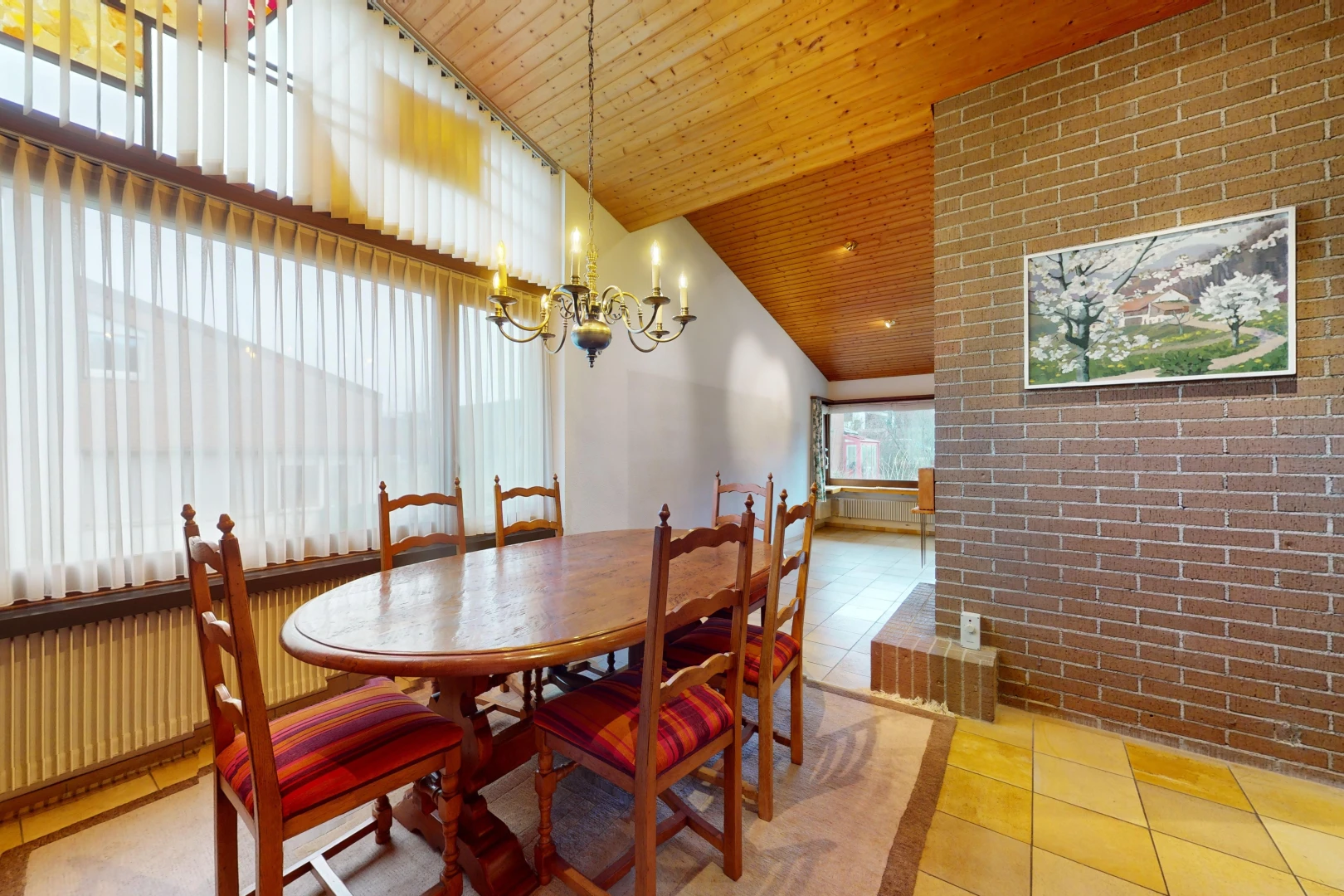 salle à manger avec lumière naturelle, lustre, mur en briques, carrelage, et plafond de bois