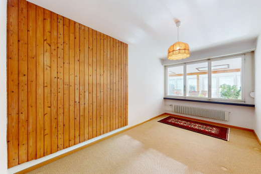 pièce vide avec radiateur, mur en bois, moquette, et lumière naturelle