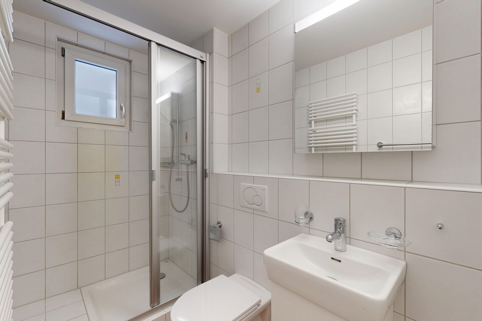 bathroom featuring a towel warming rack, a shower stall, radiator heating unit, and tile walls