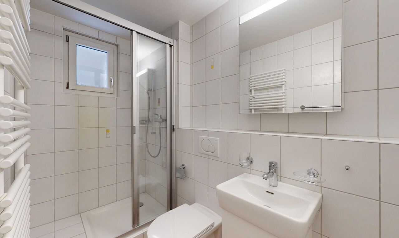 bathroom featuring a towel warming rack, a shower stall, radiator heating unit, and tile walls