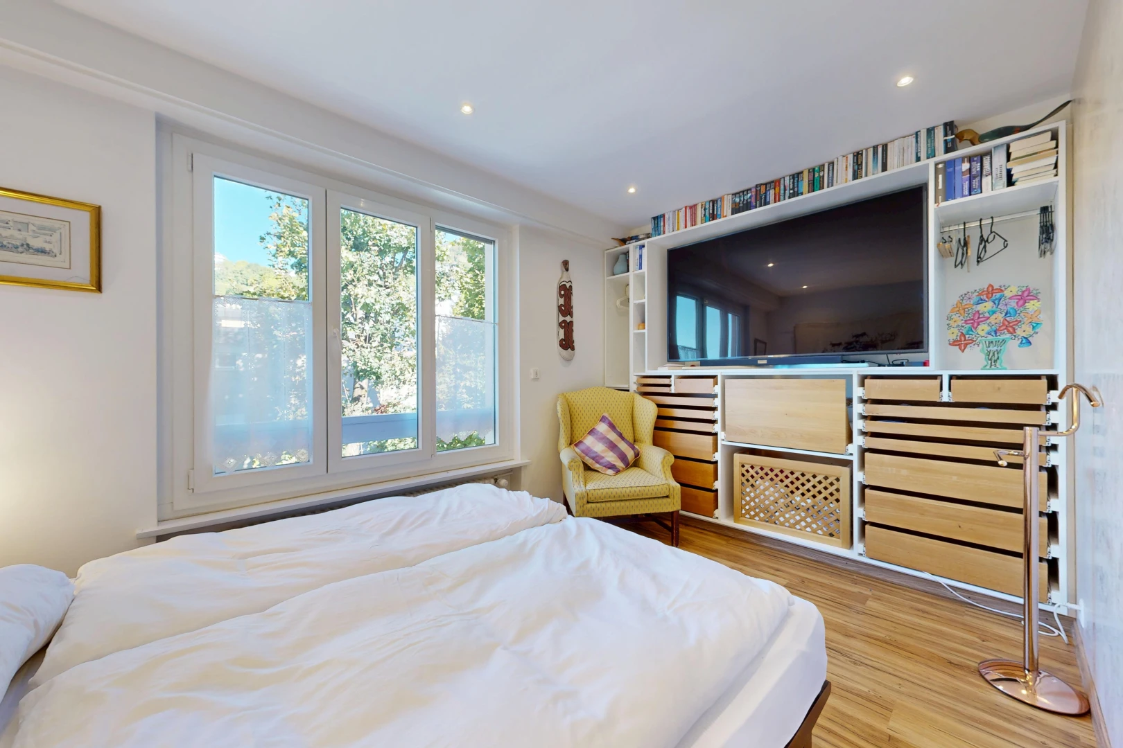 chambre avec télévision, étagères intégrées, sol en finition bois, wood finish floor, et éclairage encastré