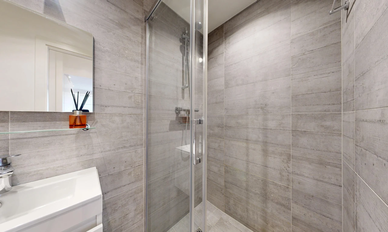 salle de bains avec miroir, douche, salle de bain complète, lavabo (ou coiffeuse selon le contexte), et inside property