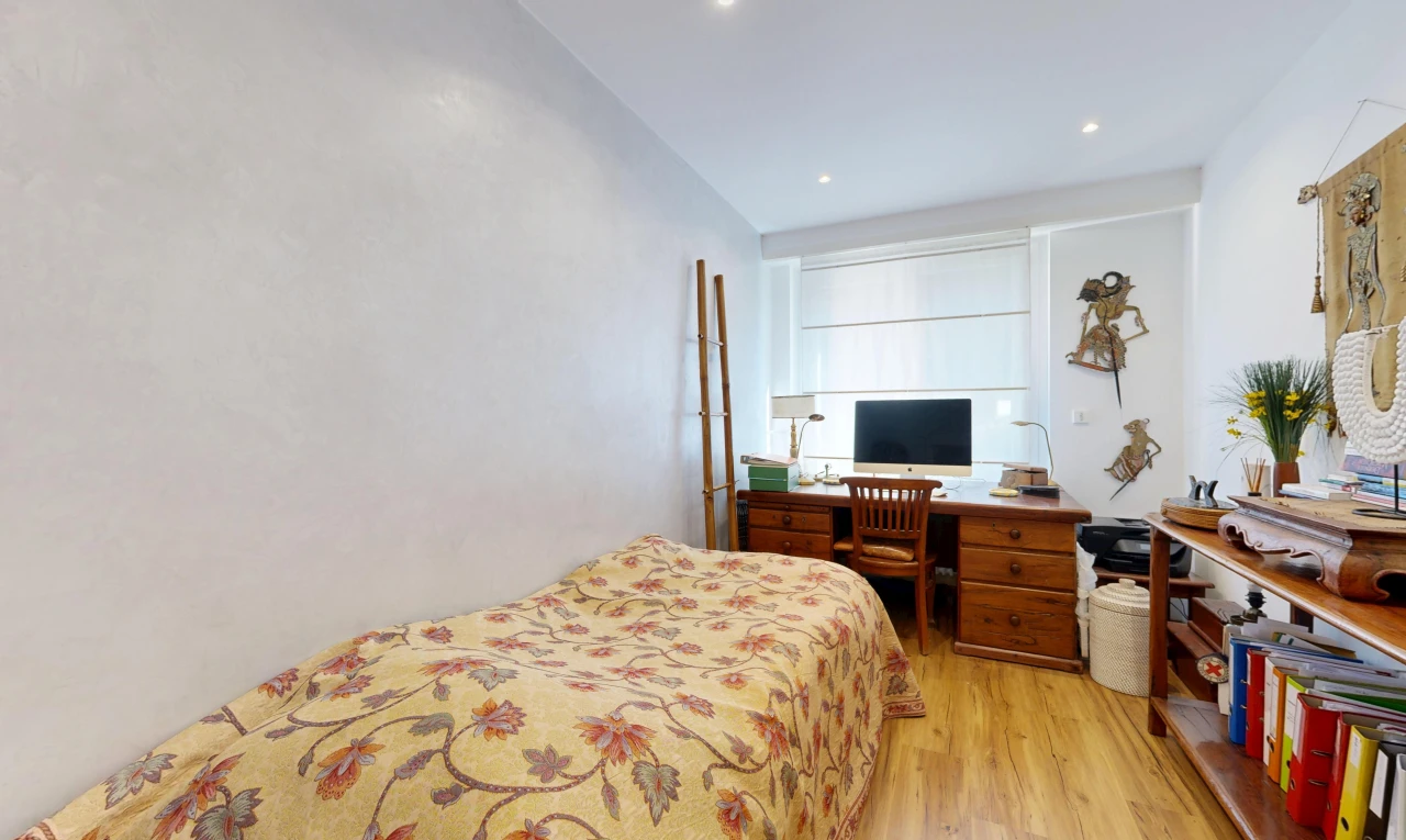 chambre avec télévision, sol en finition bois, wood finish floor, espace bureau, et éclairage encastré