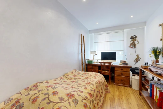 chambre avec télévision, sol en finition bois, wood finish floor, espace bureau, et éclairage encastré