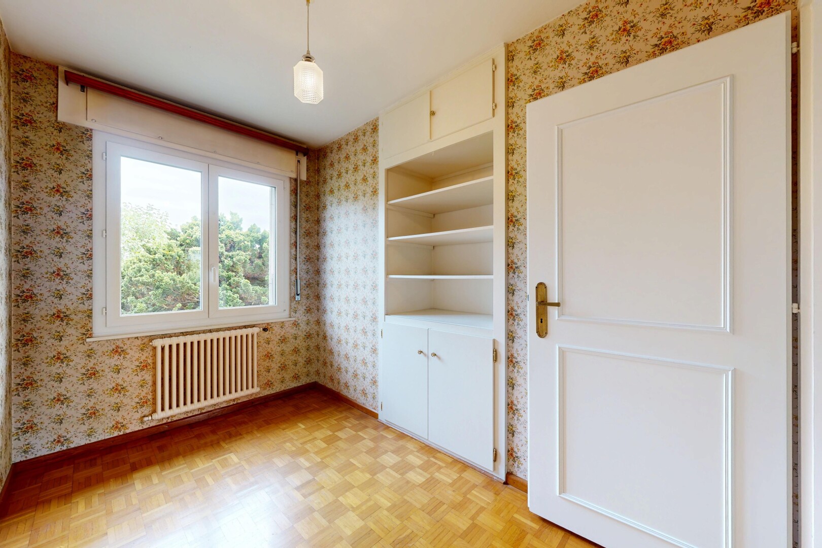 unfurnished room with parquet floors, radiator, and wallpapered walls
