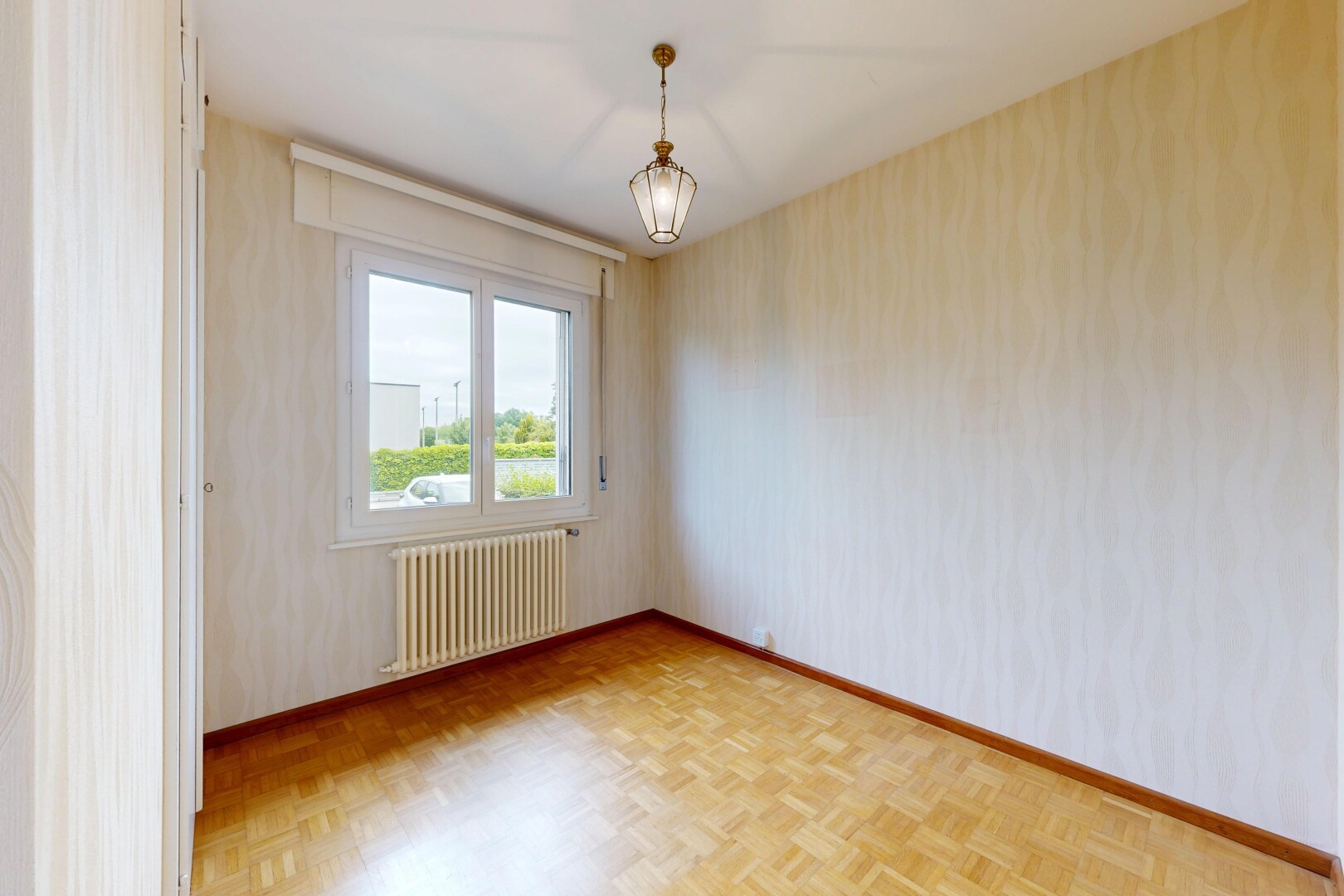 empty room featuring radiator heating unit, parquet flooring, and wallpapered walls