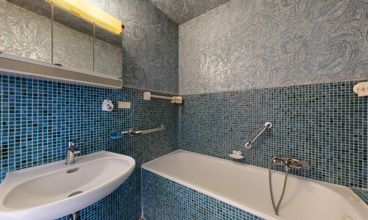bathroom featuring a bath, tile walls, and wallpapered walls