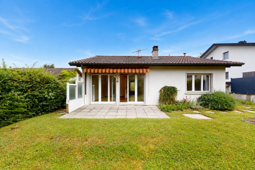 outdoor house with a patio, stucco siding, a lawn, and a chimney